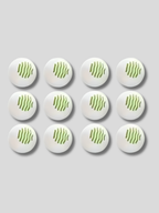 Set of 12 white shoe deodorizer balls with ventilation holes placed near suede ankle boots on a wooden surface