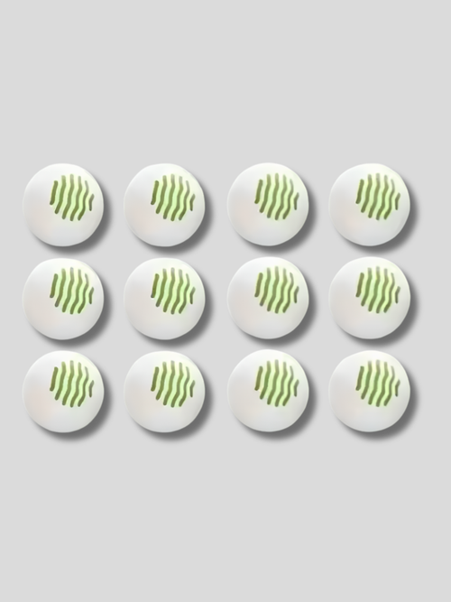 Set of 12 white shoe deodorizer balls with ventilation holes placed near suede ankle boots on a wooden surface